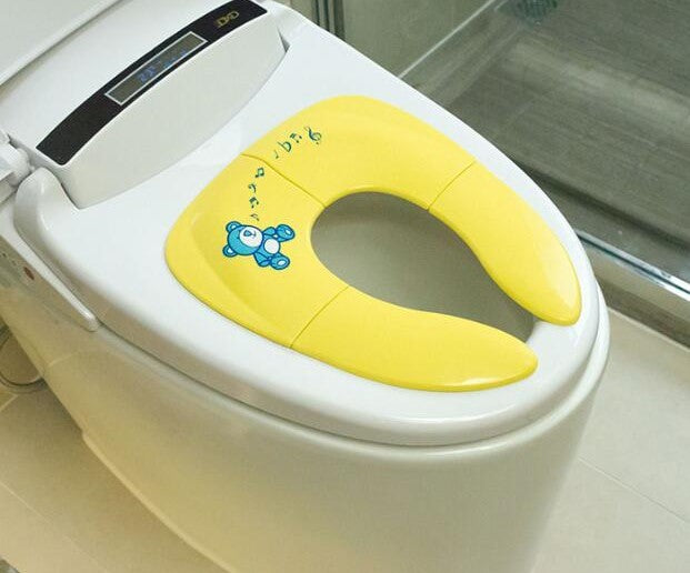 מושב אסלה מתקפל צהוב מותקן על מושב אסלה בשירותים.